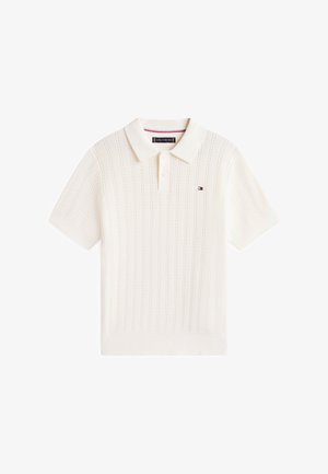 Polo bianca a maniche corte in maglia con sottili motivi verticali e un piccolo logo rosso, bianco e blu sul petto a sinistra.