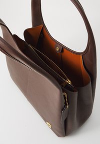 Brun läder tote-väska med en strukturerad yta, med en orange insida. Innehåller ett huvudfack, en ficka med dragkedja och guld detaljer.