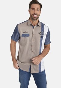 Kurzarmhemd in Beige mit blauen Akzenten, ausgestattet mit einer Brusttasche, Knöpfen und gestickten Details auf der Vorderseite.