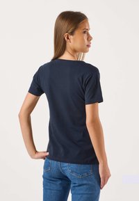 Merensininen puuvillainen t-paita, jossa on lyhyet hihat ja pyöreä pääntie. Paidalla on sileä pinta ja istuva malli. Kuvassa paita takaa.