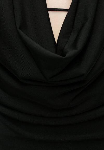 Μαύρο τοπ με υφασμάτινες πτυχώσεις, σχέδιο V λαιμόκοψης και ελαστική λεπτομέρεια στο ντεκολτέ. Η υφή είναι λεία και ριμπ.