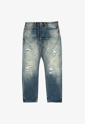Blå denimjeans med slidt effekt og flossede områder på forsiden af låret og knæsektionerne, med en rød og blå tråddetalje nær linningen.
