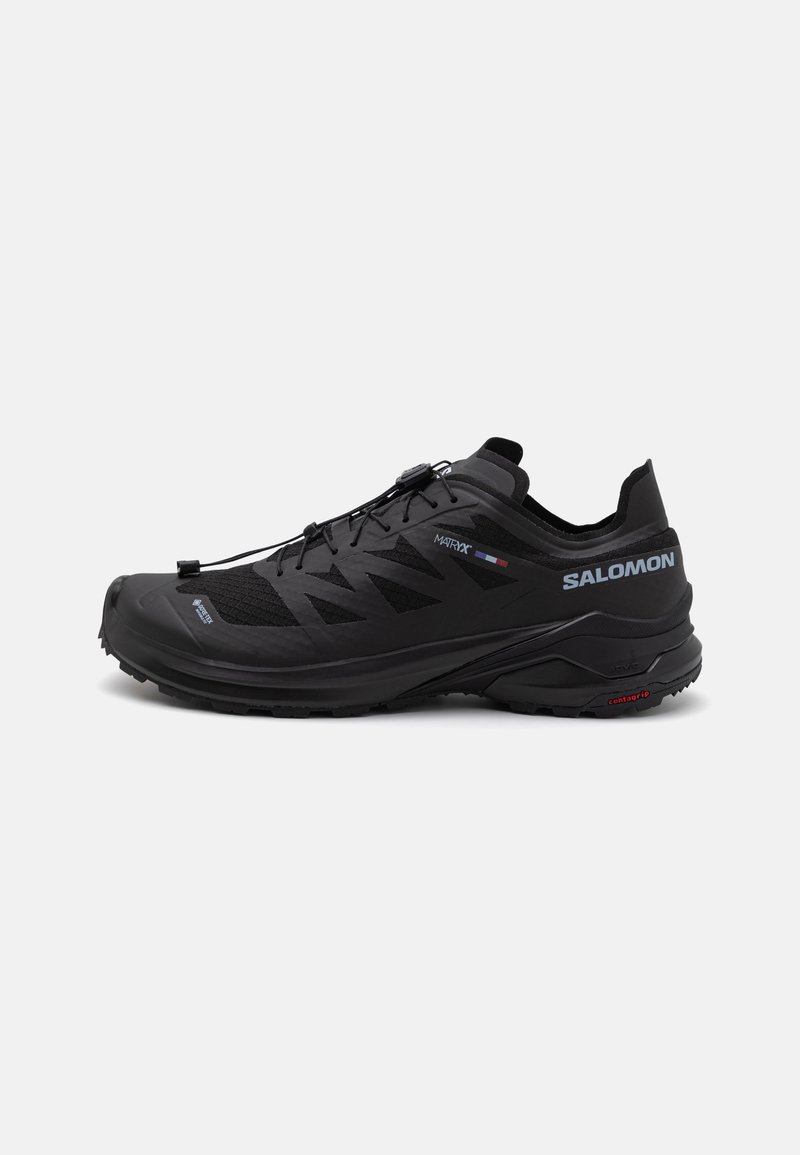 Chaussure de trail running noire avec une tige en mesh texturé, des accents réfléchissants, un système de laçage élastique et une semelle en caoutchouc robuste pour une meilleure traction.