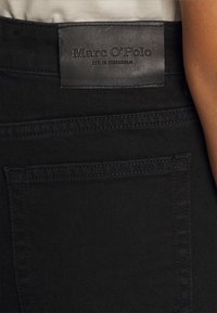 Musta farkkushortsit, joissa on nahkainen tuote-etiketti, jossa on kohokuvioitu brändimerkintä. Slim fit -muotoilu, normaali takatasku ja hienovaraiset ompeluyksityiskohdat.