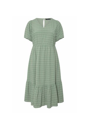 Vihreä ruutukuvioinen mekko, jossa on lyhyet puff-hihat, V-mallinen kaula-aukko ja takana avaus. Mekossa on kerroksellinen röyhelöhelma ja kevyt kangas.