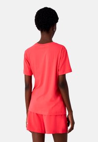 Kortærmet t-shirt i lys koral bomuld, med rund halsudskæring og afslappet pasform, parret med matchende shorts.