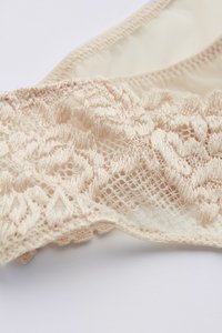 Beige spetsunderkläder med intrikata blomster mönster, nät detaljer och mjukt tyg med elastiska kanter.