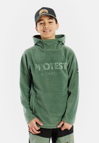Pullover in pile verde con cappuccio, dotato di tasca frontale e logo "PROTEST MCMXCIII". Il tessuto appare morbido e testurizzato. Cappuccio regolabile.