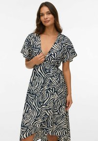 Jūras zilas un krēmkrāsas rakstaina apģērba kleita ar īsām flutter piedurknēm, dziļu V veida kakla izgriezumu un pieguļošu vidukļa saiti, ar asimetrisku apakšmalu.