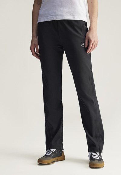 Schwarze Sporthose mit schmaler Passform, aus glattem Stoff gefertigt. Verfügt über ein Logo am linken Oberschenkel und Kontrastnähte an den Seiten.