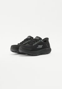 Black athletic shoes with a mesh upper, featuring a textured design, secure laces, and cushioned soles for comfort and support.
