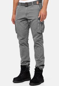 Szare spodnie cargo o slim fit, z bocznymi kieszeniami, plecionym paskiem i teksturowanym wykończeniem, w zestawieniu z czarnymi zamszowymi butami.