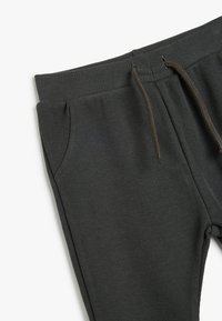 Mørkegrå ribbede joggers med elastisk talje og brun snor. Inkluderer sidelommer og en glat overflade.