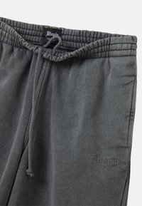 Grijze joggingbroek met een geribbelde elastische tailleband, een trekkoord en een subtiele logo geborduurd aan de zijkant. Zacht, gestructureerd stof.