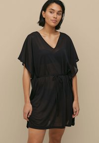 Abito coprente nero trasparente con scollatura a V, maniche corte, cintura regolabile in vita e spacchi laterali, realizzato in tessuto leggero.