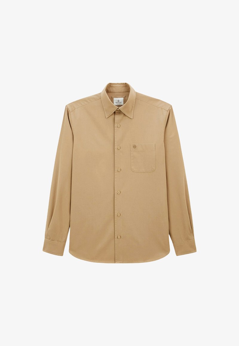 Chemise beige à manches longues en tissu lisse, avec un col boutonné, une poche sur le devant et des boutons sur le devant.