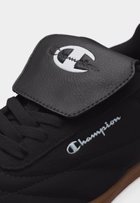 Μαύρο αθλητικό παπούτσι Champion με μαύρα κορδόνια, επενδεδυμένη γλώσσα με λευκό λογότυπο Champion και σόλα από καουτσούκ καραμέλας.