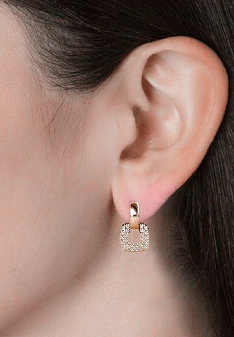 Orecchini quadrati in tonalità oro con pietre chiare scintillanti, caratterizzati da un design minimalista elegante. La superficie è liscia con una finitura lucida.