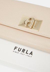 Clutch in pelle pesca con finitura testurizzata e hardware dorato, dotato di una chiusura con logo. Accompagnato da una scatola bianca con marchio.