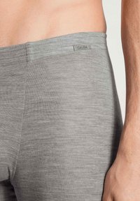 Boxer shorts in tessuto elasticizzato grigio, con texture liscia, vita piatta e etichetta discreta. Vista ravvicinata che enfatizza il materiale e la vestibilità.