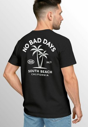 Black T-shirt featuring white text "NO BAD DAYS" and palm tree graphic on the back, with "SOUTH BEACH CALIFORNIA" below. Short sleeves, casual fit.