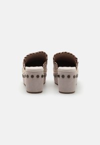 Mules en cuir tressé marron avec une base en suède gris clair et des rivets métalliques ronds sur les côtés. Design à talon bloc épais.