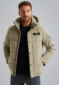 Vaaleanbeige corduroy-puffatakki, jossa on huppu, etuvetoketju, nappisuljenta ja logo-patch rinnassa. Systeeminen ja pehmustettu muotoilu.