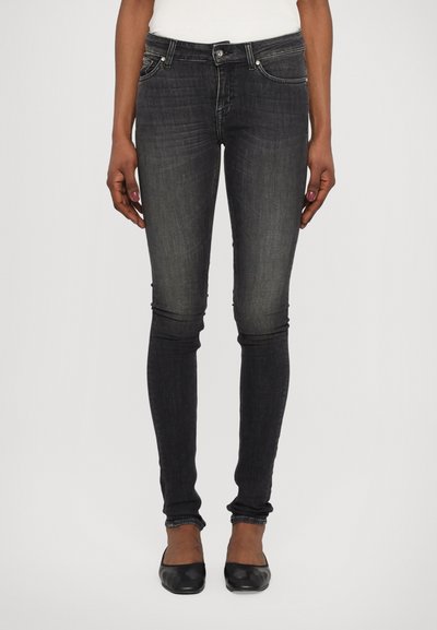 Zwarte skinny jeans van denim, met vervaagde details. Het ontwerp omvat vijf zakken en zilveren hardware accenten. Plat zwarte schoenen gedragen.