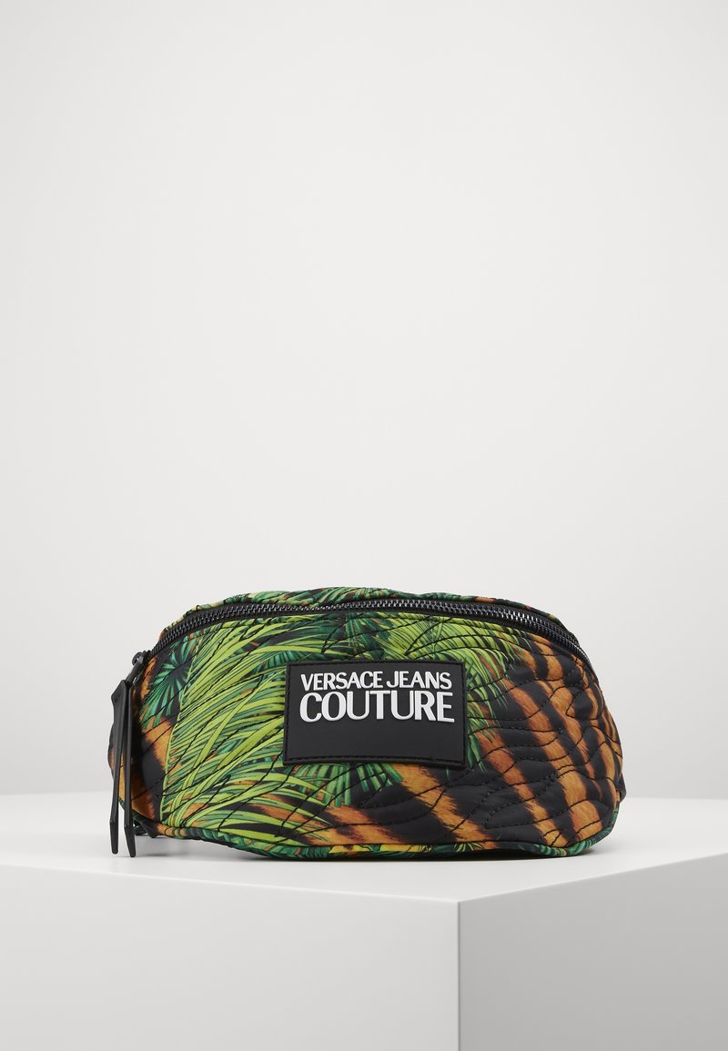 Banane matelassée Versace Jeans Couture avec imprimé feuille de palmier vert et rayures tigre marron, fermeture éclair noire et patch logo sur le devant.