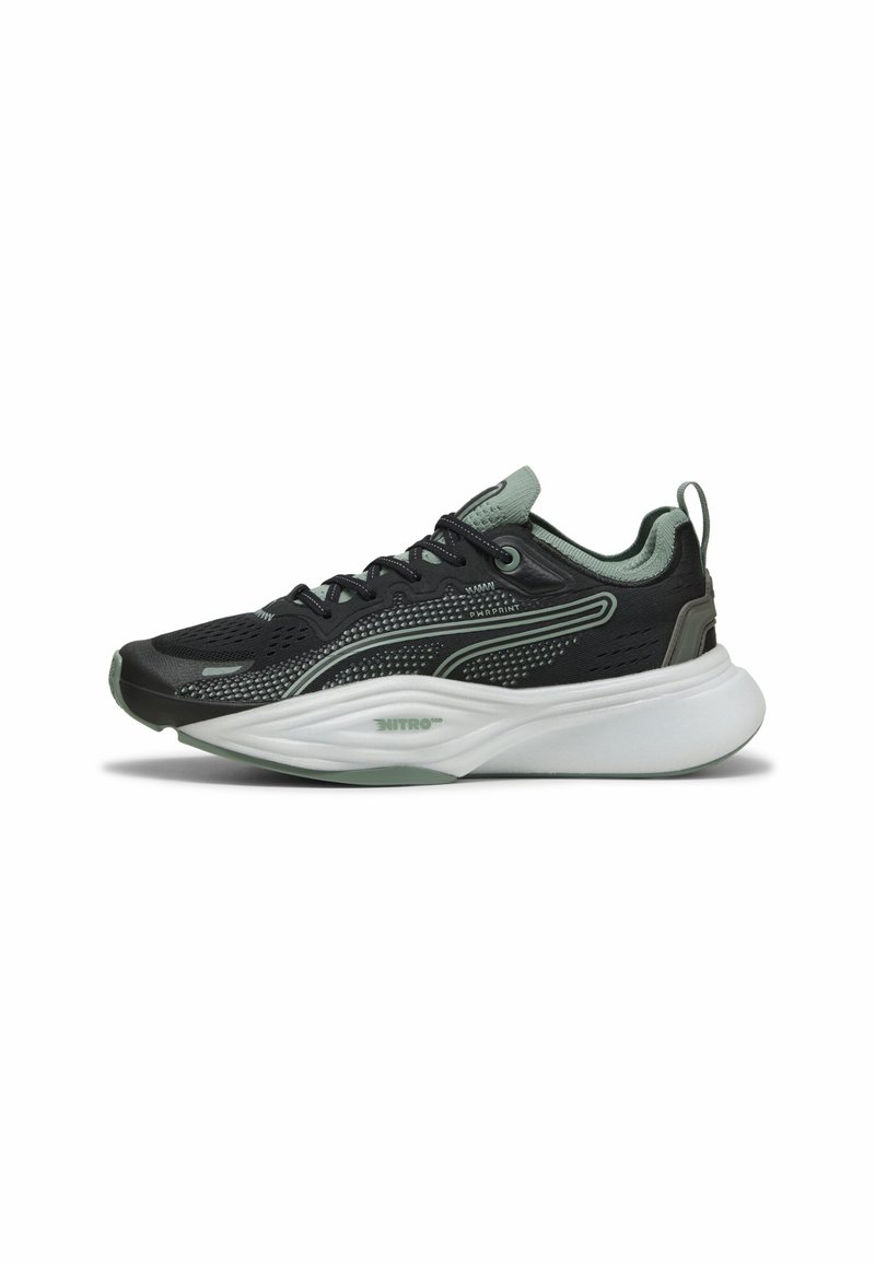 Chaussure de sport noire avec tige en mesh, accents vert clair, détails texturés, semelle intermédiaire blanche épaisse et fermeture à lacets. Logo notable sur le côté.
