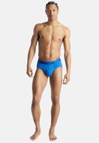 Blå herrunderkläder med en tight passform, som har resårmidja och svarta accentlinjer framtill. Slät textur, minimalistisk design.