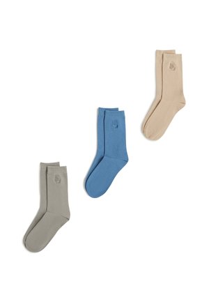 Drei Paare schlichte Knöchelsocken in Beige, Blau und Hellgrau, jeweils mit einem kleinen gestickten Logo nahe dem oberen Rand.