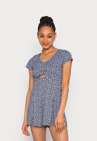 Vestido azul-marinho com padrão floral branco, mangas curtas em formato de ombreiro, um detalhe frontal torcido com um recorte e um design de saia rodada.