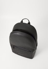 Zaino in pelle nera con una finitura testurizzata, parte superiore arrotondata, scomparti con doppia zip, tasca anteriore con zip e dettaglio del logo sulla parte anteriore.