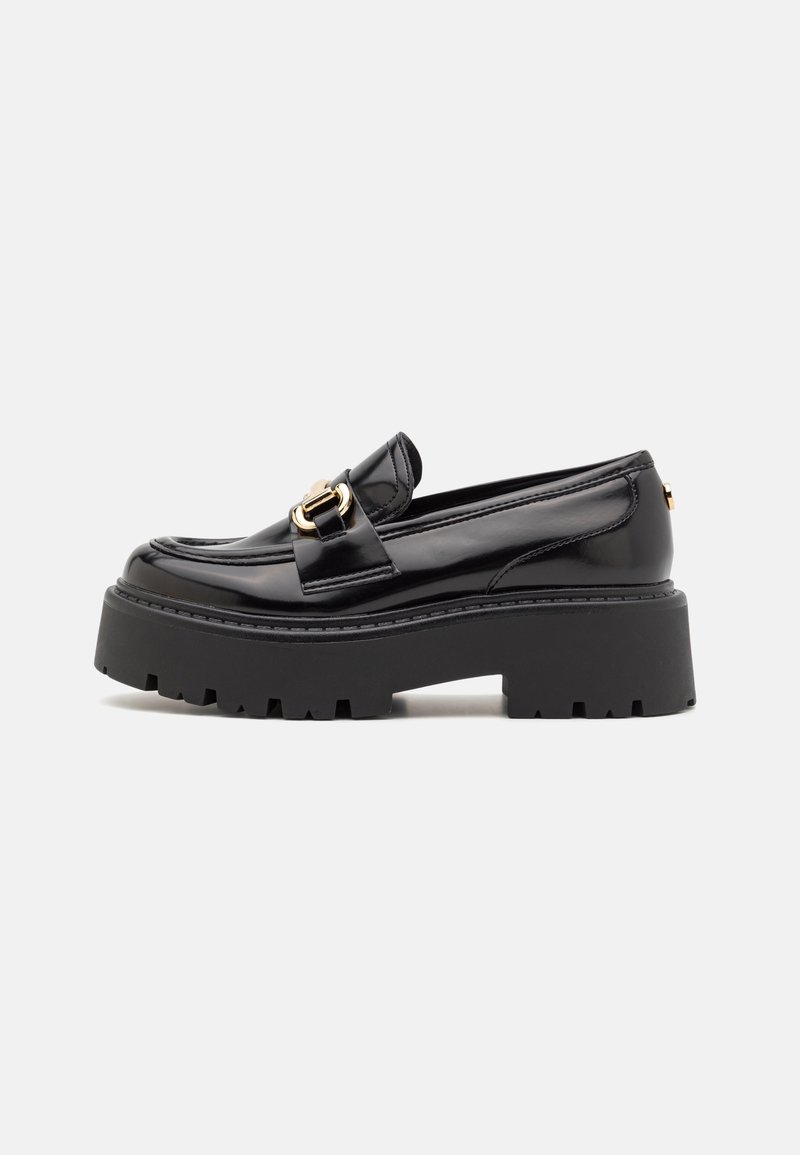 Mocassin en cuir noir brillant avec semelle crantée épaisse et détail de boucle métallique dorée, vue de côté sur fond uni.