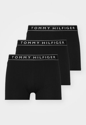 Boxer shorts neri in cotone con un elastico bianco con il logo "TOMMY HILFIGER", caratterizzati da una vestibilità aderente e una texture liscia, indossati da un modello maschile.