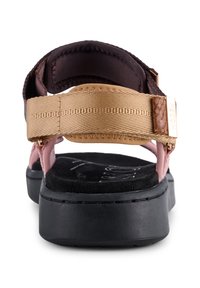 Rosa och guld sandal med ett strukturerat rem och mjuk, svart sula. Har en stadig svart sula och en metallisk logotypdetalj.