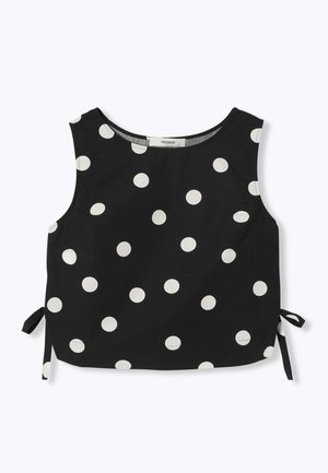Haut court noir sans manches avec de gros pois blancs et détails avec lien sur le côté, col rond, posé à plat sur fond blanc.