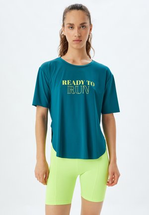 Teal atletisk skjorte med korte ærmer og teksten "READY TO RUN" i gul, parret med tætsiddende neon-gule shorts. Glat stofstruktur.