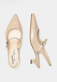 Chaussures Mary Jane en cuir verni beige avec un bout pointu, une bride à la cheville réglable et un petit talon carré. Texture lisse avec un minimum de détails.