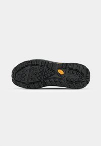 Suela de zapato negra con un dibujo profundo y con patrón para mayor tracción. Logo de Vibram en amarillo, indicando el uso de material de alto rendimiento.