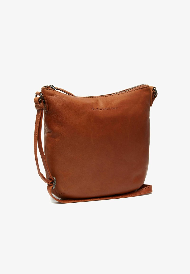 Ruskean nahkainen olkalaukku, jossa on sileä pinta, vetoketjukiinnitys ja säädettävä hihna. Mukana pyöristetty yläosa ja hillitty logotieto.