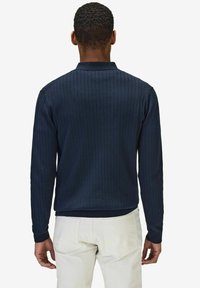 Marinblå långärmad skjorta med ribbad textur, knappad krage och figursydd midja. Har kontrasterande manschetter och en avslappnad passform.