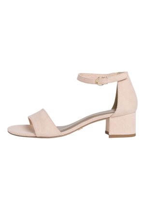 Beige mokkasandaler med åpen tå, blokkhel og justerbar ankelreim med en liten gullspenne, sett fra siden på hvit bakgrunn.