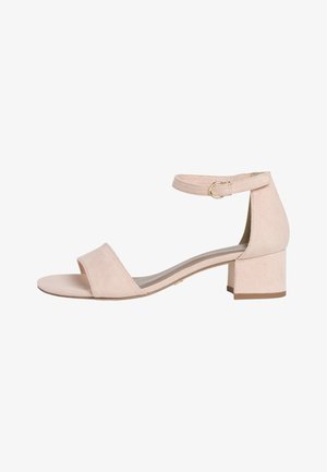 Sandale ouverte en daim beige avec talon carré et sangle de cheville réglable, dotée d'une petite boucle en or, vue de côté sur fond blanc.