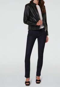 Zwarte leren bomberjack met een opstaande kraag, ritssluiting en gequiltte zoom; gecombineerd met donkere denim rechte jeans en zwarte hakken.