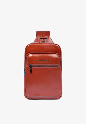 Mochila de cuero marrón con diseño elegante, bolsillo frontal con cremallera y acentos azules. Cuenta con correa ajustable y logo de la marca en el frente.