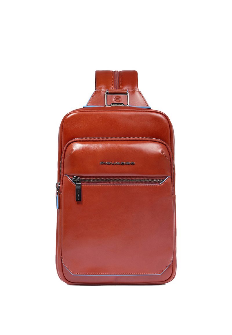 Mochila de cuero marrón con diseño elegante, bolsillo frontal con cremallera y acentos azules. Cuenta con correa ajustable y logo de la marca en el frente.