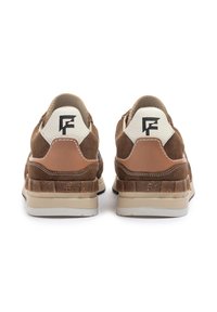 Zapatillas de ante marrón con acentos de cuero en tonos marrón claro, un talón texturizado y un parche de tela blanca con un logo negro en la parte trasera.