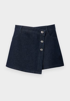Mini-jupe en jean bleu foncé avec devant asymétrique, boutons argentés, passants de ceinture et poches avant sur fond uni.